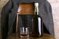 Bottle of rum and old-fashioned glass on the retro wooden chair, male coat on it Royalty Free Stock Photo