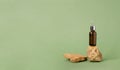 A bottle of serum oil cosmetic on an abstract podium made of natural materials stones plants green pastel background. Royalty Free Stock Photo