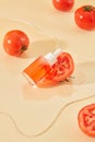 A bottle of serum is placed next to half a tomato on a transparent acrylic sheet. The concept of homemade cosmetics with natural