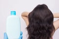 Bottle with shampoo on the background of a girl with lush beautiful hair, copy space