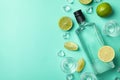 Bottle and shots of vodka, limes and ice on mint background, top view