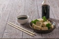 A bottle of soy sauce and slices of tofu cheese on a wooden table. Soy cheese. Royalty Free Stock Photo