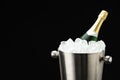 Bottle of sparkling wine in cooler bucket on black background, closeup. Space for text Royalty Free Stock Photo