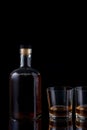 bottle of strong alcohol brandy with glasses on black background