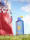Bottle of suntan lotion and bag with beach items in grass close-up Royalty Free Stock Photo