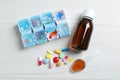 Bottle of syrup, dosing spoon and pills on white wooden table, flat lay. Cold medicine Royalty Free Stock Photo