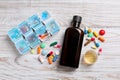 Bottle of syrup, measuring cup, weekly pill organizer and pills on white wooden table, flat lay. Cold medicine Royalty Free Stock Photo