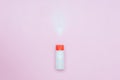 Bottle of Talcum baby powder on pink background. Powder spilled from white container, top view flatlay Royalty Free Stock Photo