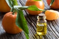 A bottle of tangerine essential oil with tangerines in the background Royalty Free Stock Photo