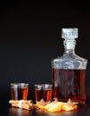 A bottle and two glasses of cognac with tangerine pieces and chocolates on a black background Royalty Free Stock Photo