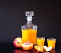 A bottle and two glasses of peach liqueur and sliced ripe fruits on a black background Royalty Free Stock Photo