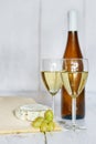 Bottle and two glasses of white wine, white grape and camembert cheese on a wooden background Royalty Free Stock Photo