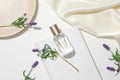 A bottle of unbranded perfume is displayed on a white podium alongside lavender flowers. Lavender can help reduce stress, anxiety