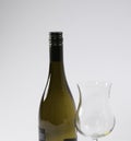 A bottle of unopened white wine next to an empty wine glass