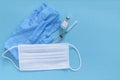 Bottle with vaccine  protective gloves  mask and medicine syringe with vaccine on blue background. Concept of vaccination and Royalty Free Stock Photo