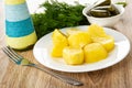 Bottle of vegetable oil, dill, bowl with gherkins, plate with baked potato, fork on wooden table Royalty Free Stock Photo