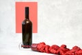 A bottle and a vintage glass on a gray-red background. Red wine is poured out of the glass, imitated by a silk handkerchief. Selec Royalty Free Stock Photo