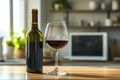 A bottle is visible in the background as soft sunlight shines down on a red wine glass positioned on a kitchen Royalty Free Stock Photo