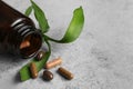 Bottle with vitamin capsules and green leaves on table Royalty Free Stock Photo