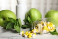 Bottle with vitamin pills, apples and mint on marble table Royalty Free Stock Photo