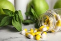 Bottle with vitamin pills, apples and mint on marble table, closeup Royalty Free Stock Photo