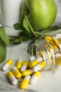 Bottle with vitamin pills, apples and mint on white marble table, closeup Royalty Free Stock Photo