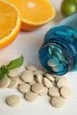 Bottle with vitamin pills and orange on white wooden table, closeup Royalty Free Stock Photo