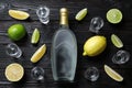 Bottle of vodka, citrus fruits and shot glasses on wooden table, flat lay. Space for design