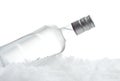 Bottle of vodka lying on ice on white background