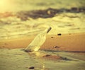Bottle in water on beach at sunset, retro instagram effect. Royalty Free Stock Photo