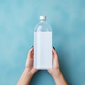 Empty Sparkling Water Bottle Mockup With Woman\'s Hand On Blue Background