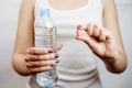 Bottle of water in woman hand tablet in hand, vitamins with water Royalty Free Stock Photo