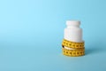 Bottle of weight loss pills with measuring tape on color background. Royalty Free Stock Photo