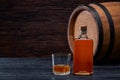Bottle of whiskey on a black wooden in oak barrels