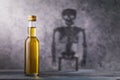 A bottle of whiskey with a shadow in the shape of a skeleton. Concept on the harm of alcohol and harmful habits of man