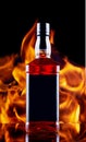 A bottle of whiskey stands on a glass bar top against the background of a fire flame. Royalty Free Stock Photo