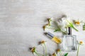 A bottle of white perfume and flowers with leaves.