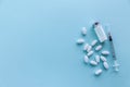 A bottle of white powder, a syringe and a bunch of white pills on a gray-blue background on the right, top view