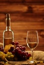 Bottle of white wine, glass and grape on a sack in wooden interior Royalty Free Stock Photo