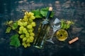 A bottle of white wine with glasses and grapes. Leaves of grapes. Top view. On a black wooden background. Royalty Free Stock Photo