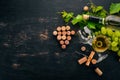 A bottle of white wine with glasses and grapes. Leaves of grapes. Top view. On a black wooden background. Royalty Free Stock Photo