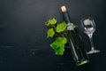 A bottle of white wine with glasses and grapes. Leaves of grapes. Top view. On a black wooden background. Royalty Free Stock Photo
