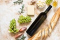 A bottle of white wine, grapes, cheese, butter, honey, baguette, shallot and rosemary