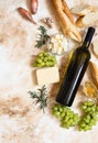 A bottle of white wine, grapes, cheese, butter, honey, baguette, shallot and rosemary