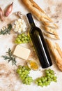 A bottle of white wine, grapes, cheese, butter, honey, baguette, shallot and rosemary