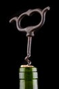 A bottle of wine and a corkscrew on a dark table. Opening good wine with a corkscrew Royalty Free Stock Photo