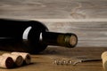 Bottle of wine with corkscrew on wooden background