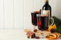 Bottle of wine, cups of mulled wine and ingredients on wooden background