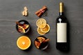 Bottle of wine, cups of mulled wine and ingredients on wooden background