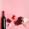 A bottle of wine an empty glass of a bunch of red grapes on a gentle pink background. Flat layout top view. Copy space Royalty Free Stock Photo